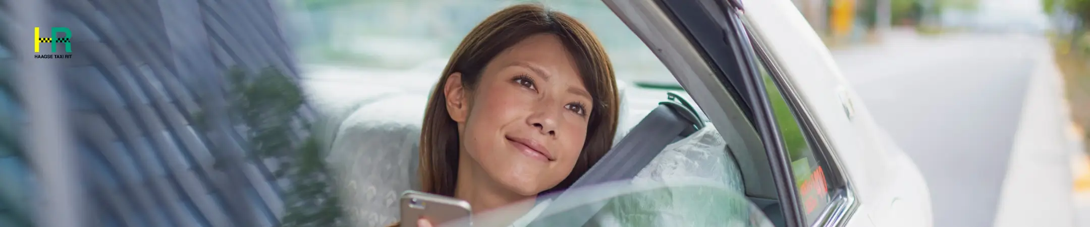 Passenger relaxing in the back seat, looking out the window – taxi den haag and bob taxi den haag for comfortable travel.